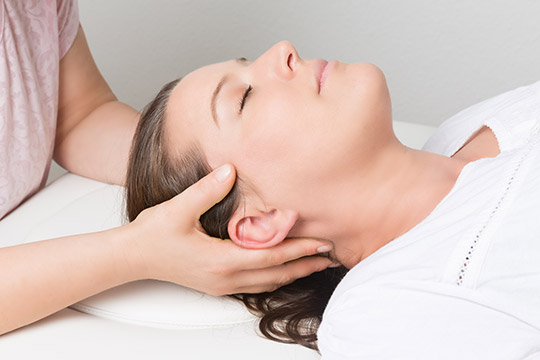 Eine Frau genießt die Entspannung, die bei der Handhaltung der craniosacralen Hinterhauptschale eingeleitet werden kann.